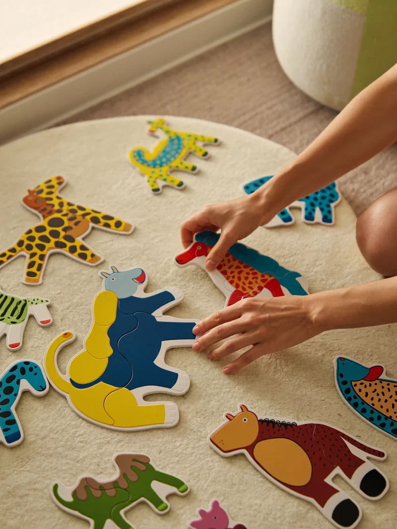 Kartonowe puzzle podłogowe z zwierzakami i dziecięce dłonie na macie do zabawy